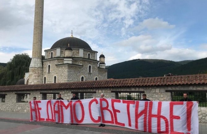 Krivokapić i sveštenici ispred Husein-pašine džamije sa transparentom 